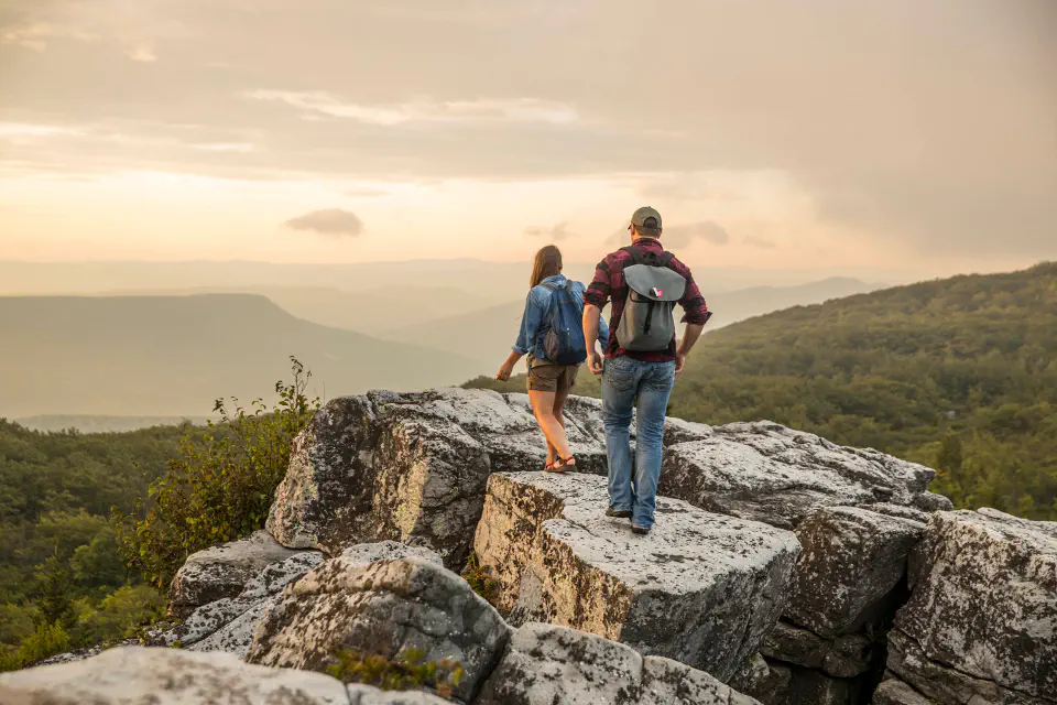 A man and woman walking on rocks with a mountainous view