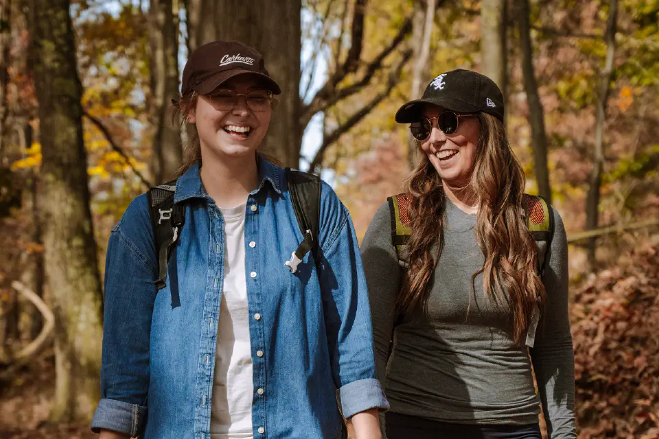 Two women walk on a trail laughing 