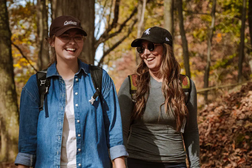 Two women laughing and smiling walking down a trail