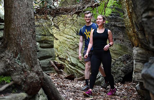 Two people hiking through the many boulders at Coopers Rock State Forest, WV.