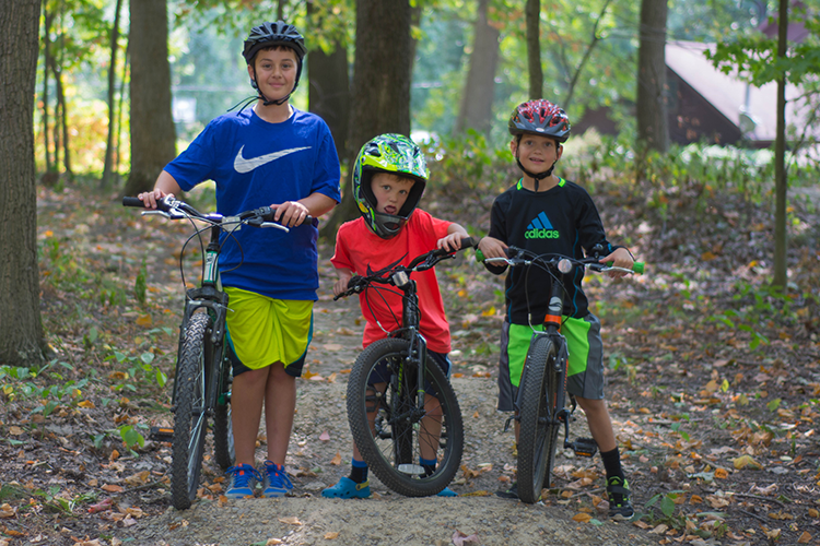 three kids on bikes in the woods