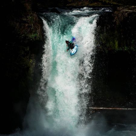 Man in kayak going over waterfall