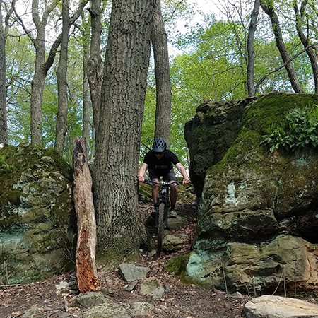 Abe Johnson mountain biking on a rocky trail.