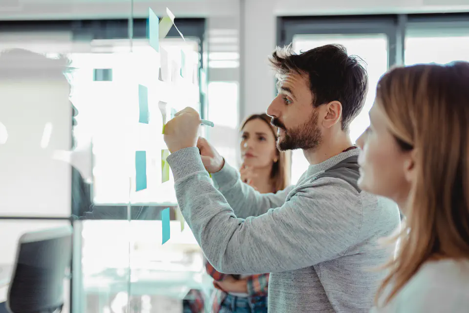 Three people putting sticky notes on a wall